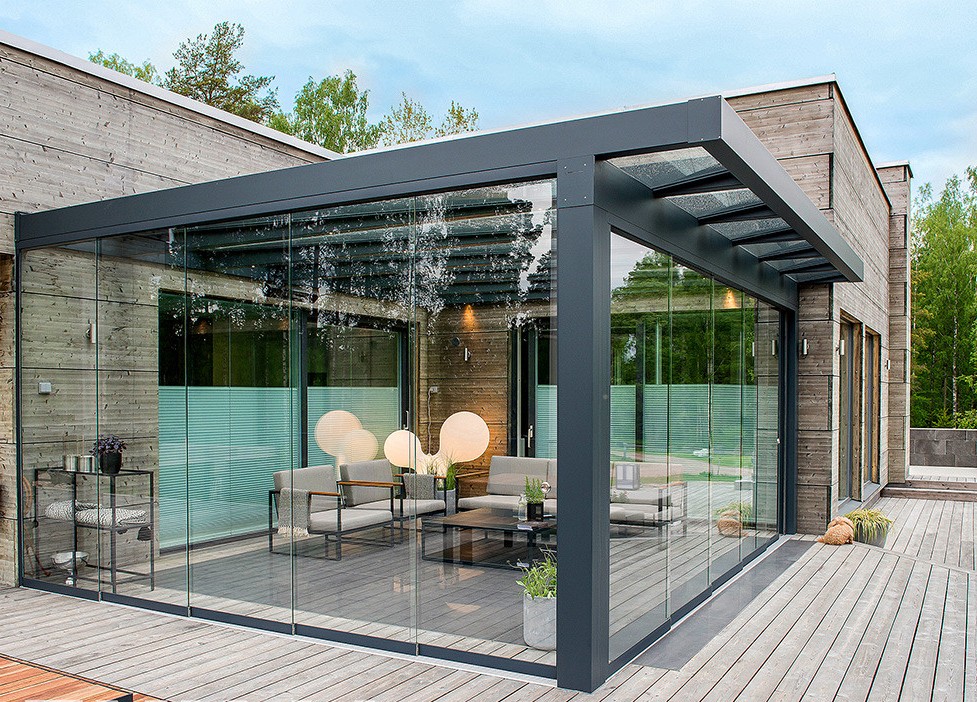 A premium fully-enclosed glass garden room with chandelier-style lighting at a modern wood-clad home